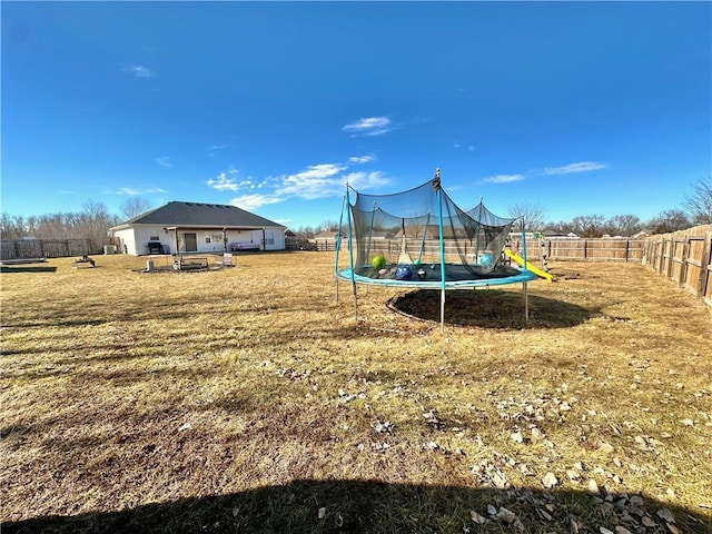 view of jungle gym featuring a trampoline, a fenced backyard, and a lawn