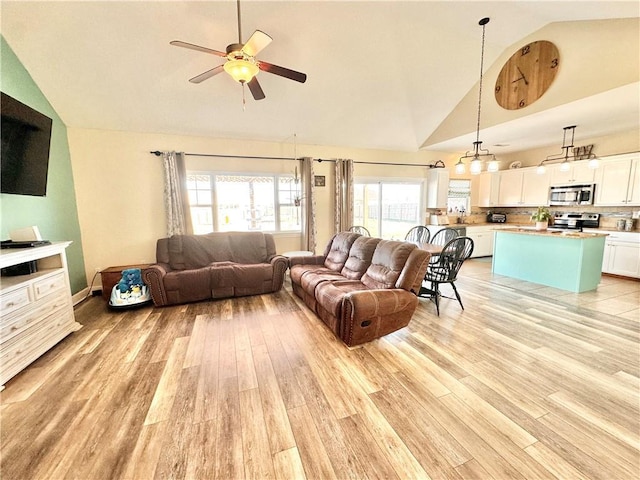 living area with ceiling fan, high vaulted ceiling, and light wood finished floors