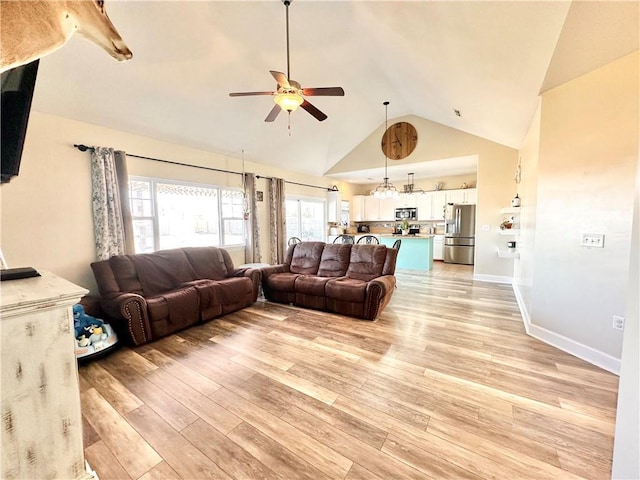 living room featuring high vaulted ceiling, light wood-style flooring, baseboards, and ceiling fan