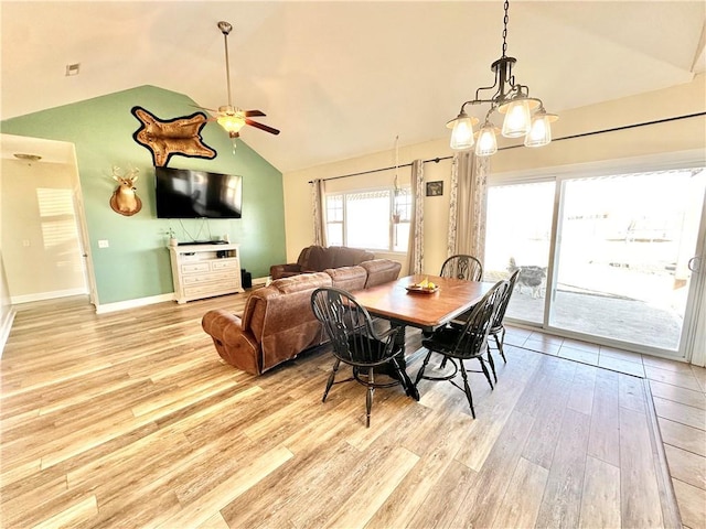 dining space featuring light wood finished floors, baseboards, vaulted ceiling, and a ceiling fan