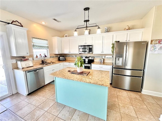 kitchen with stainless steel appliances, a kitchen island, a sink, visible vents, and white cabinets