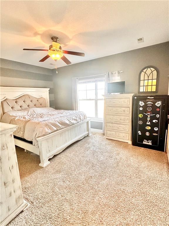 carpeted bedroom with a ceiling fan, visible vents, and a textured ceiling