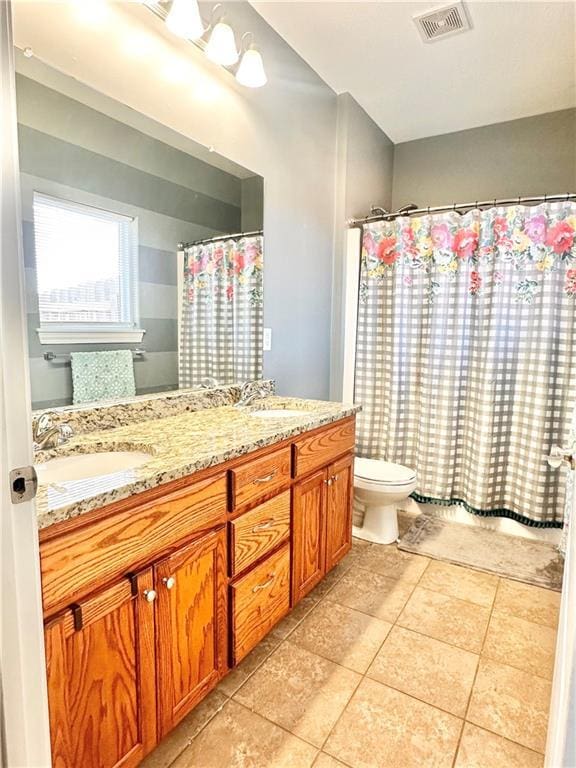 bathroom with toilet, a sink, visible vents, tile patterned floors, and double vanity