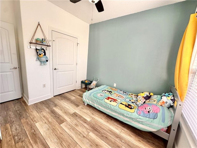 bedroom featuring a ceiling fan, baseboards, and wood finished floors