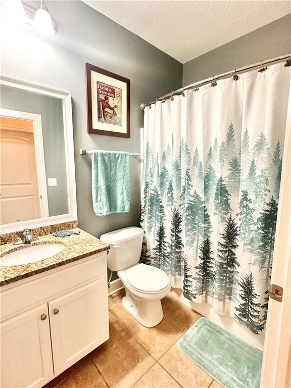 bathroom with toilet, tile patterned floors, curtained shower, a textured ceiling, and vanity