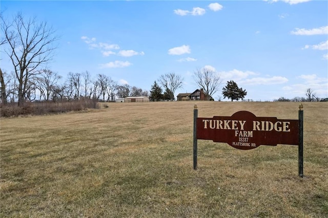 community / neighborhood sign with a lawn and a rural view