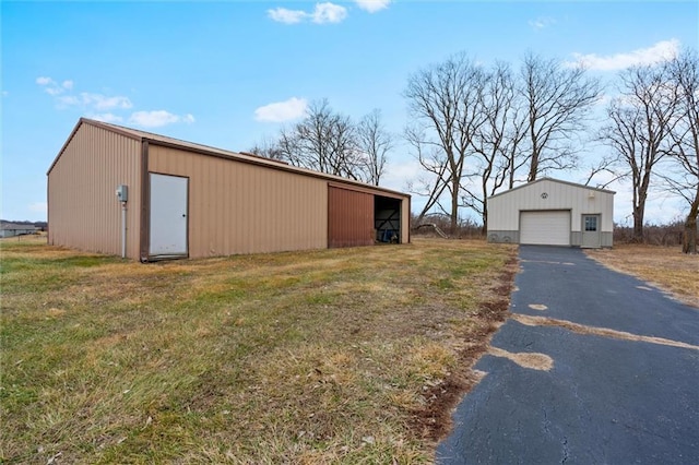 view of pole building featuring driveway and a lawn