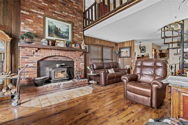 living area with wooden walls, a textured ceiling, and hardwood / wood-style flooring