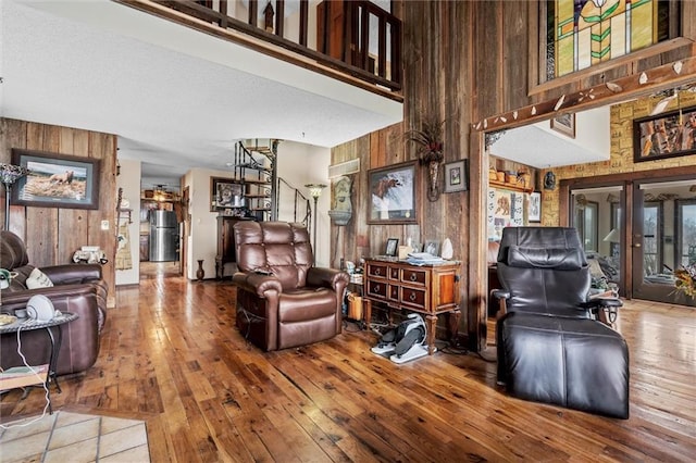 living room with wood walls, a high ceiling, and hardwood / wood-style flooring