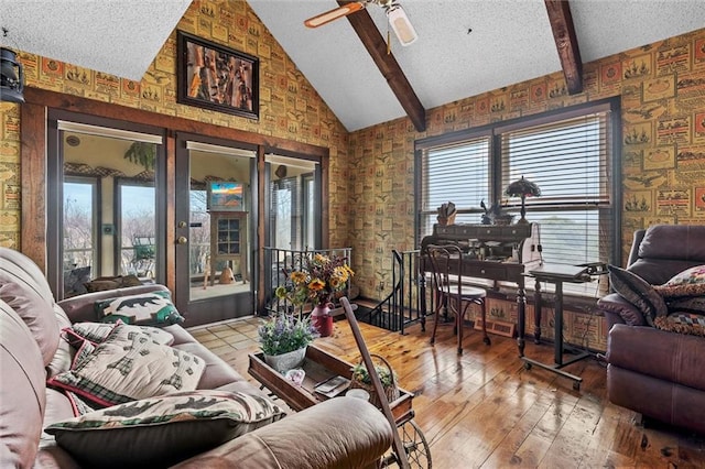 living area with vaulted ceiling with beams, hardwood / wood-style flooring, ceiling fan, and a textured ceiling