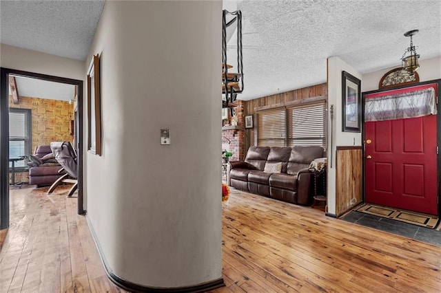 foyer with wood-type flooring, wood walls, and a textured ceiling