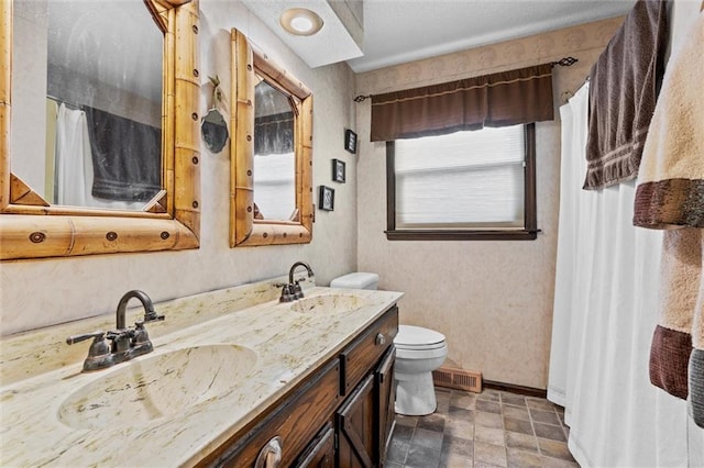 bathroom with visible vents, a sink, toilet, and double vanity