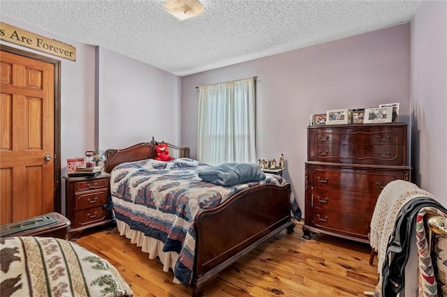 bedroom with a textured ceiling and wood finished floors