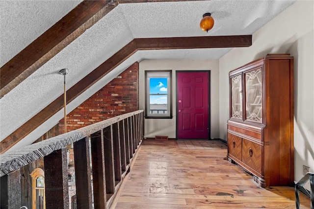 hallway featuring lofted ceiling with beams, a textured ceiling, and light wood-style floors