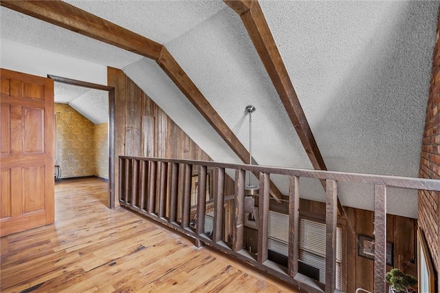 additional living space featuring vaulted ceiling with beams, wood-type flooring, and a textured ceiling