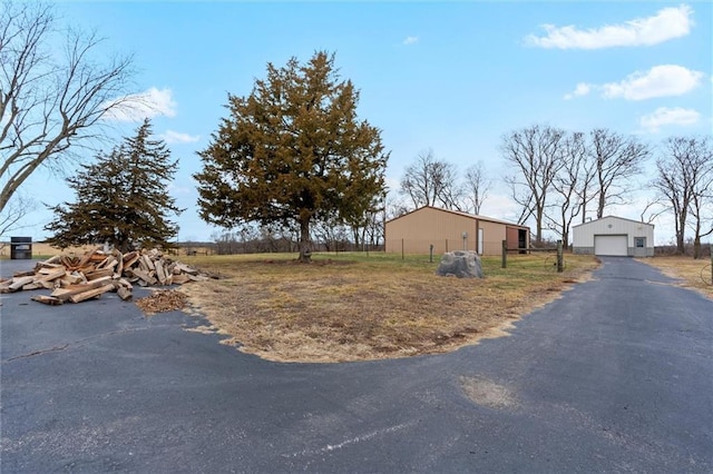 view of yard featuring an outbuilding, fence, a garage, a pole building, and driveway