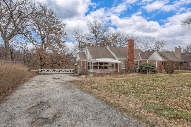 view of front of house featuring central AC, aphalt driveway, a front lawn, and brick siding