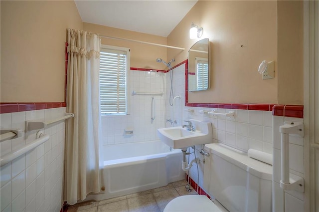 full bath featuring shower / tub combo, toilet, a wainscoted wall, tile patterned floors, and tile walls