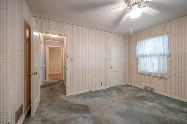 unfurnished room featuring wallpapered walls, carpet, visible vents, and baseboards