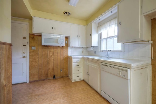 kitchen with white appliances, a sink, visible vents, white cabinets, and tile counters