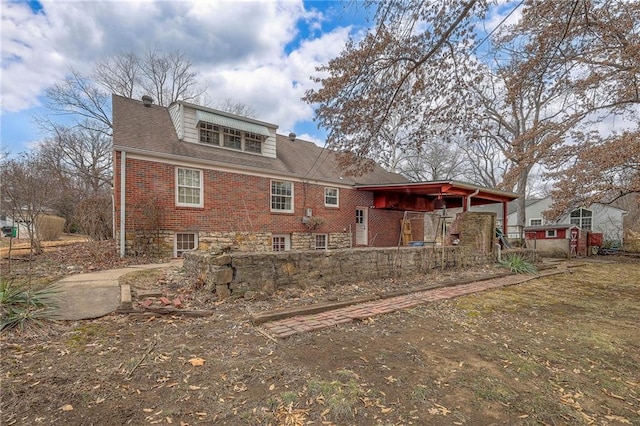 back of property featuring brick siding and roof with shingles