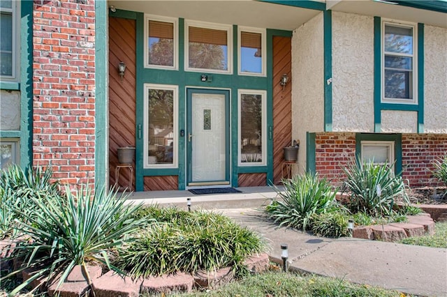 view of exterior entry with brick siding and stucco siding