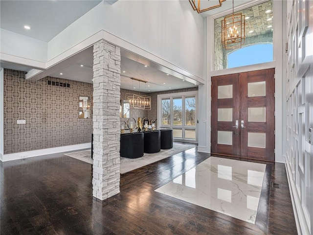 entryway with ornate columns, a chandelier, wood finished floors, and french doors