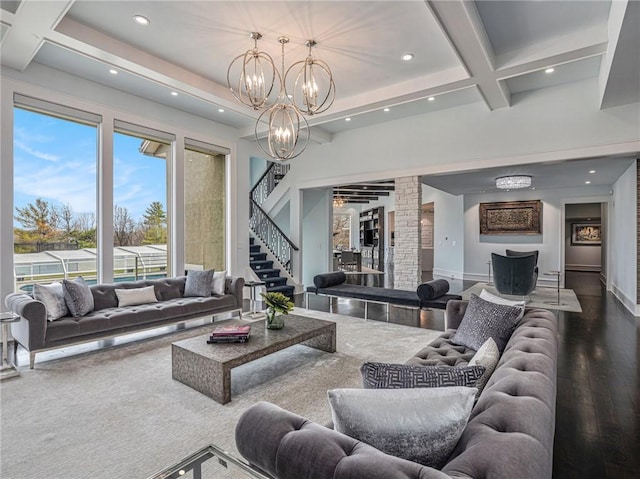 living room with a chandelier, coffered ceiling, wood finished floors, stairway, and beam ceiling