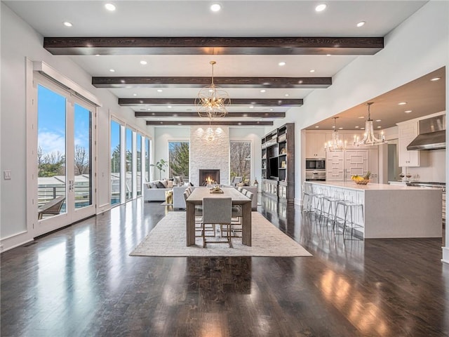 dining room with an inviting chandelier, dark wood-style floors, a large fireplace, and recessed lighting