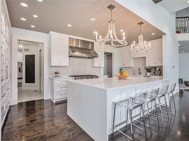 kitchen featuring a spacious island, visible vents, backsplash, white cabinets, and wall chimney range hood