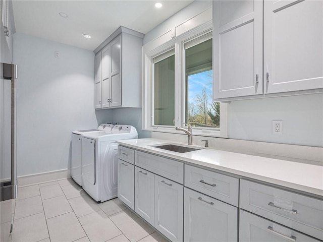 laundry room with light tile patterned floors, separate washer and dryer, a sink, baseboards, and cabinet space