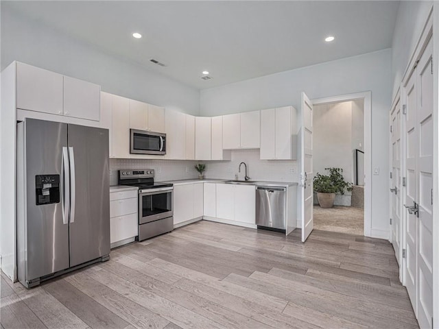 kitchen featuring stainless steel appliances, light wood-type flooring, backsplash, and visible vents