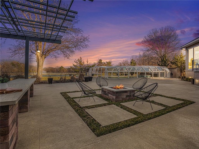 patio terrace at dusk with an outdoor fire pit and a pergola