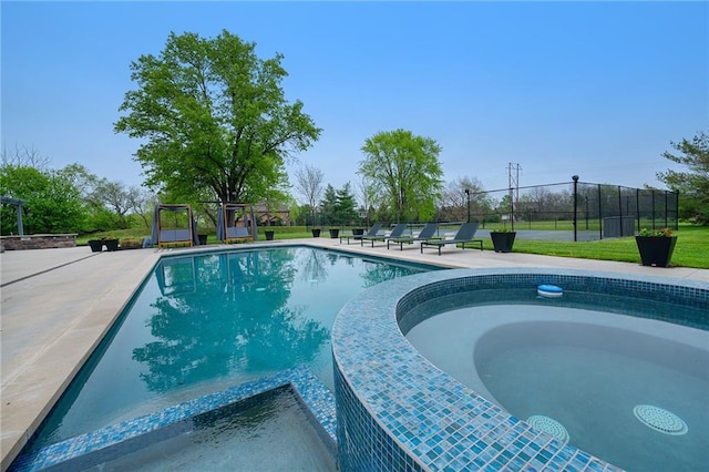 view of pool with a pool with connected hot tub, fence, and a patio