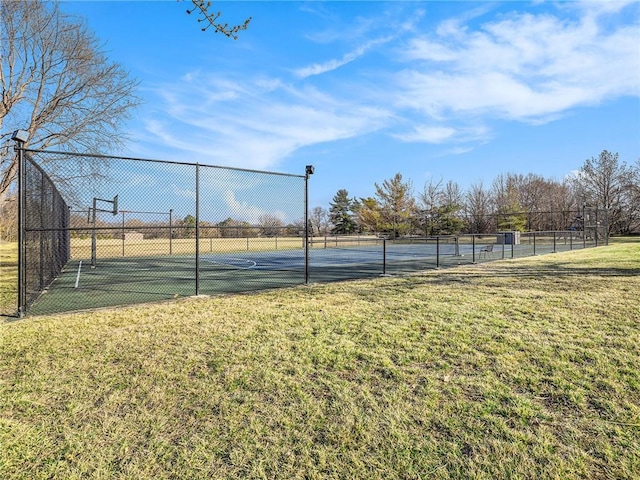 view of tennis court with community basketball court, a lawn, and fence