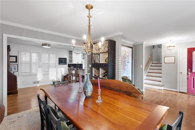 dining room with baseboards, stairway, ornamental molding, wood finished floors, and a notable chandelier