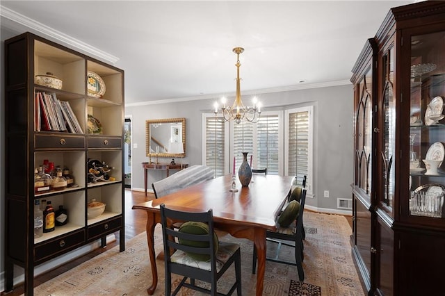 dining area featuring a notable chandelier, visible vents, crown molding, and light wood-style floors