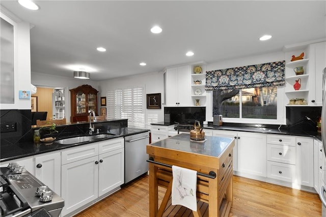 kitchen with a sink, open shelves, white cabinetry, and stainless steel appliances