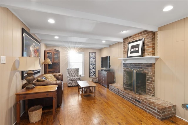 living room featuring beamed ceiling, recessed lighting, a fireplace, and wood finished floors