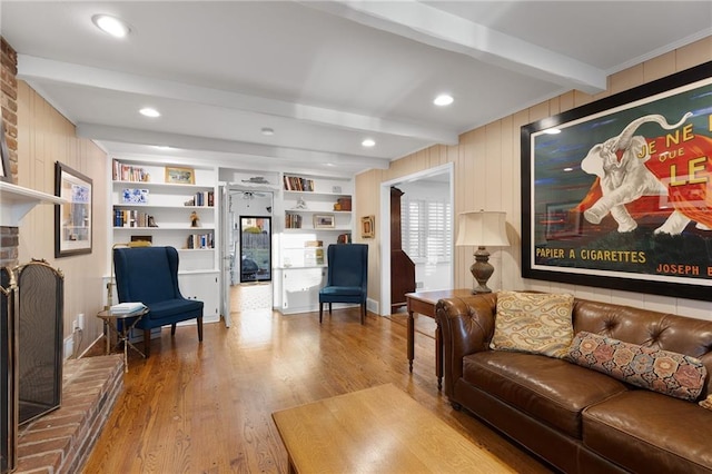 living room with beamed ceiling, built in shelves, wood finished floors, recessed lighting, and a brick fireplace