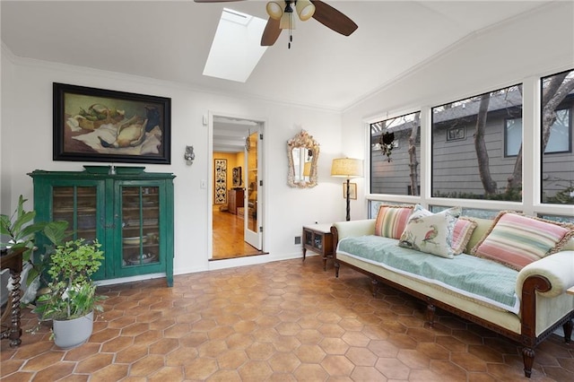 living room featuring vaulted ceiling with skylight, a ceiling fan, and ornamental molding