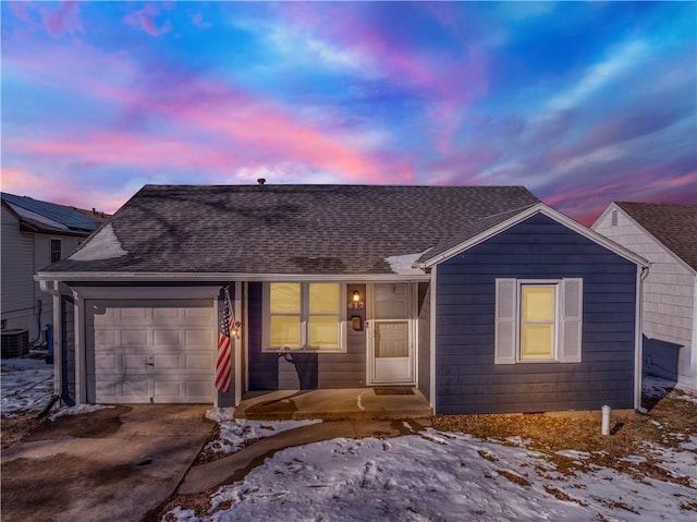 ranch-style home featuring a garage, central air condition unit, driveway, and roof with shingles