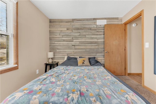 bedroom with carpet, wood walls, and baseboards