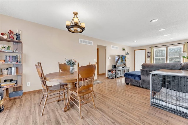 dining space featuring light wood-style flooring, visible vents, and baseboards