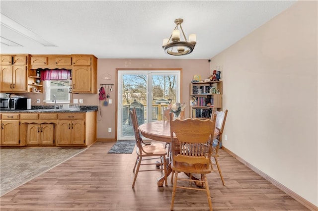 dining space with a chandelier, light wood-type flooring, and baseboards