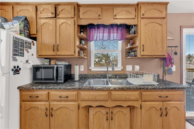 kitchen with open shelves, stainless steel microwave, dark countertops, and a sink