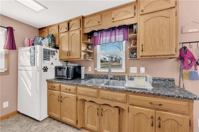 kitchen featuring baseboards, stainless steel microwave, freestanding refrigerator, open shelves, and a sink