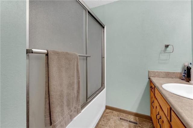 bathroom featuring baseboards, visible vents, vanity, and combined bath / shower with glass door