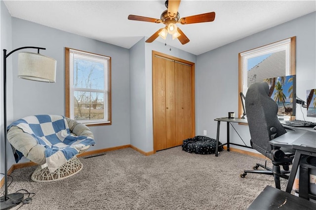 office area featuring carpet floors, visible vents, baseboards, and ceiling fan