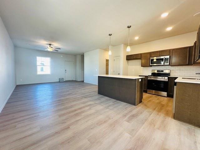 kitchen with decorative backsplash, a ceiling fan, open floor plan, light countertops, and stainless steel appliances